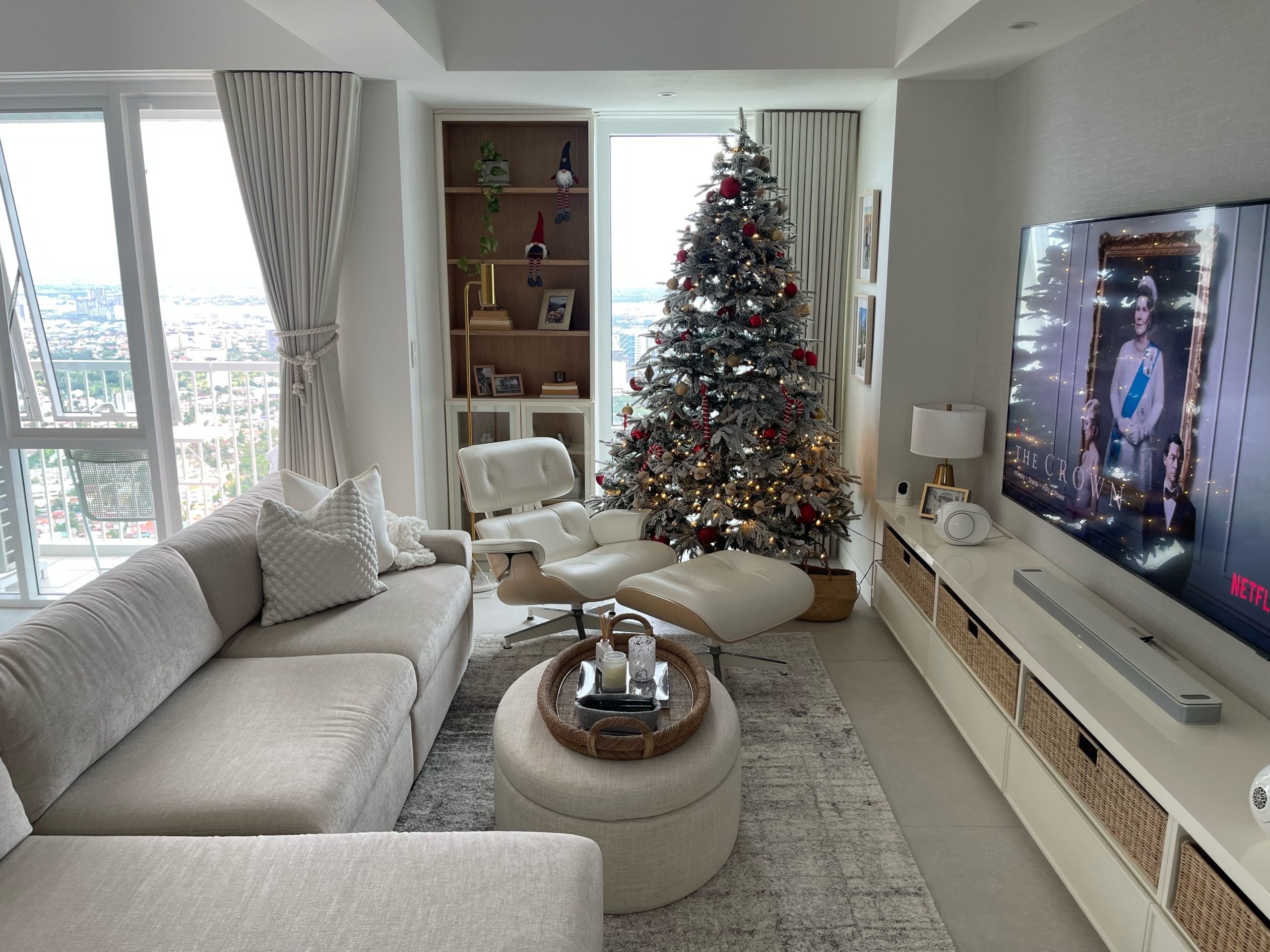 couch with rugs, christmas tree, windows, table